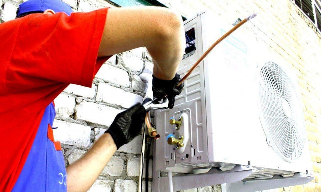 a person is repairing ac outdoor unit