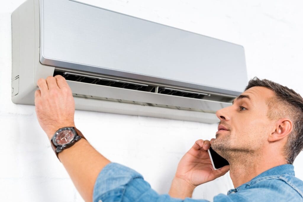 a man talking on phone and pressing the rest button of his air conditioner.