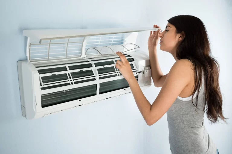 a woman opened indoor unit of air conditioner and looking inside it.